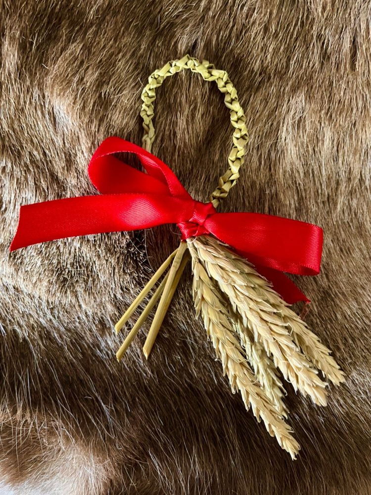 Four stalks of dried wheat have been woven together and looped to make the spikes and the ends dangle, tied with red ribbon.