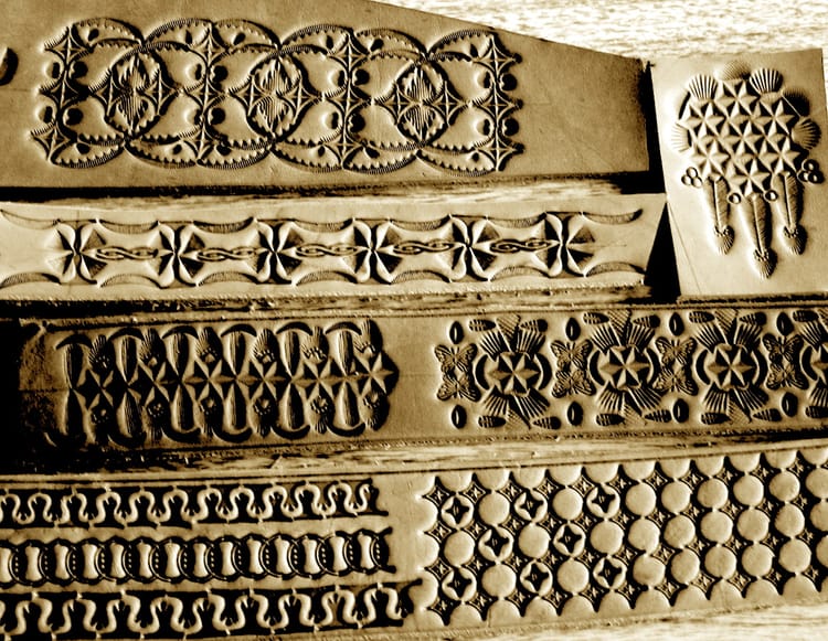 Strips of leather stamped with various repeating geometric or flowery patterns. There is a sepia tone fi