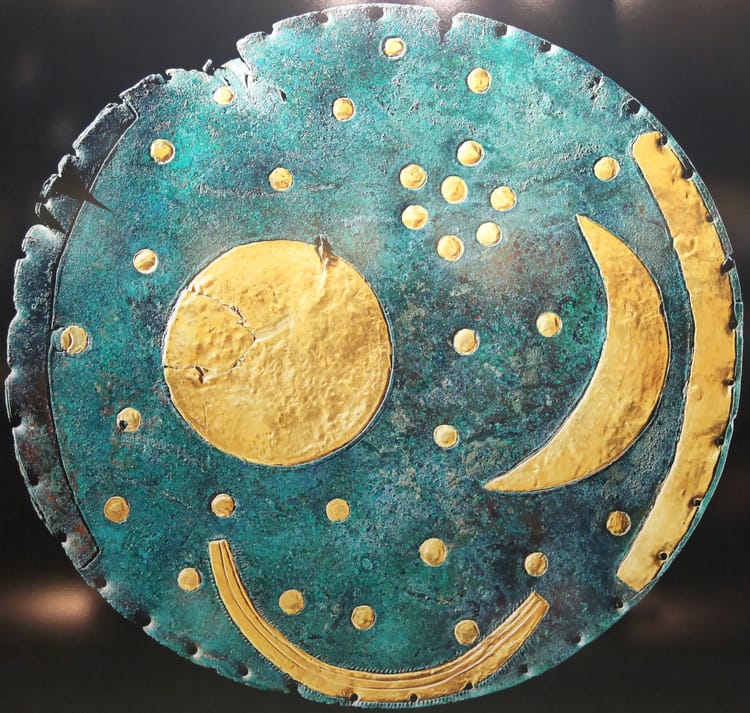 A twelve-inch diameter disk of bluish bronze set with gold celestial objects in an expressive style.