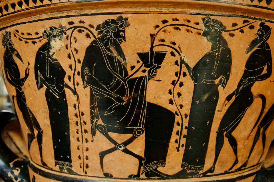 A work of Greek pottery with black figures on an orange background. The central figure is a bearded man with a cup and vines.