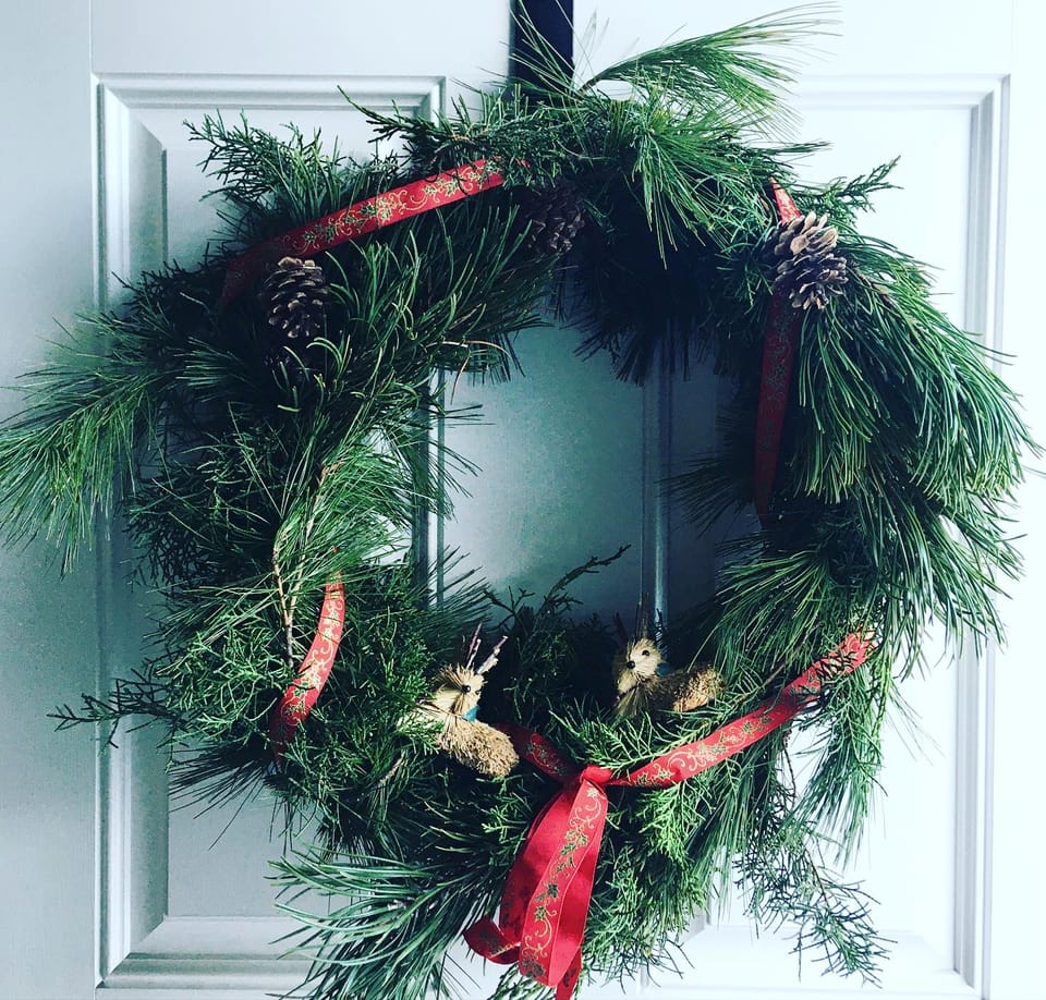 Red pine, scotch pine, and cedar woven into a circle, tied with a red ribbon, set with pinecones and jackalope figurines.