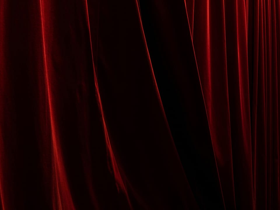 Dramatically lit folds of a red velvet curtain.